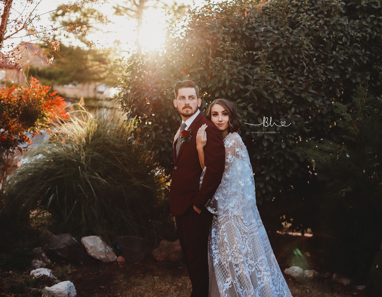 A sunset wedding portrait amid natural garden landscaping with golden backlighting.