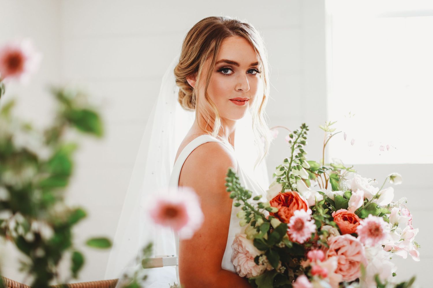 Wedding portrait of a bride with elegant hair and makeup holding a lush floral bouquet.
