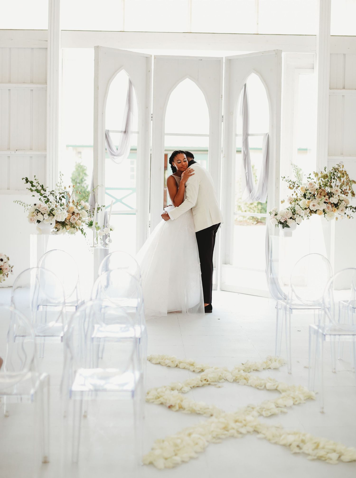 Modern white chapel interior with clear chairs and floral petal aisle decorations.