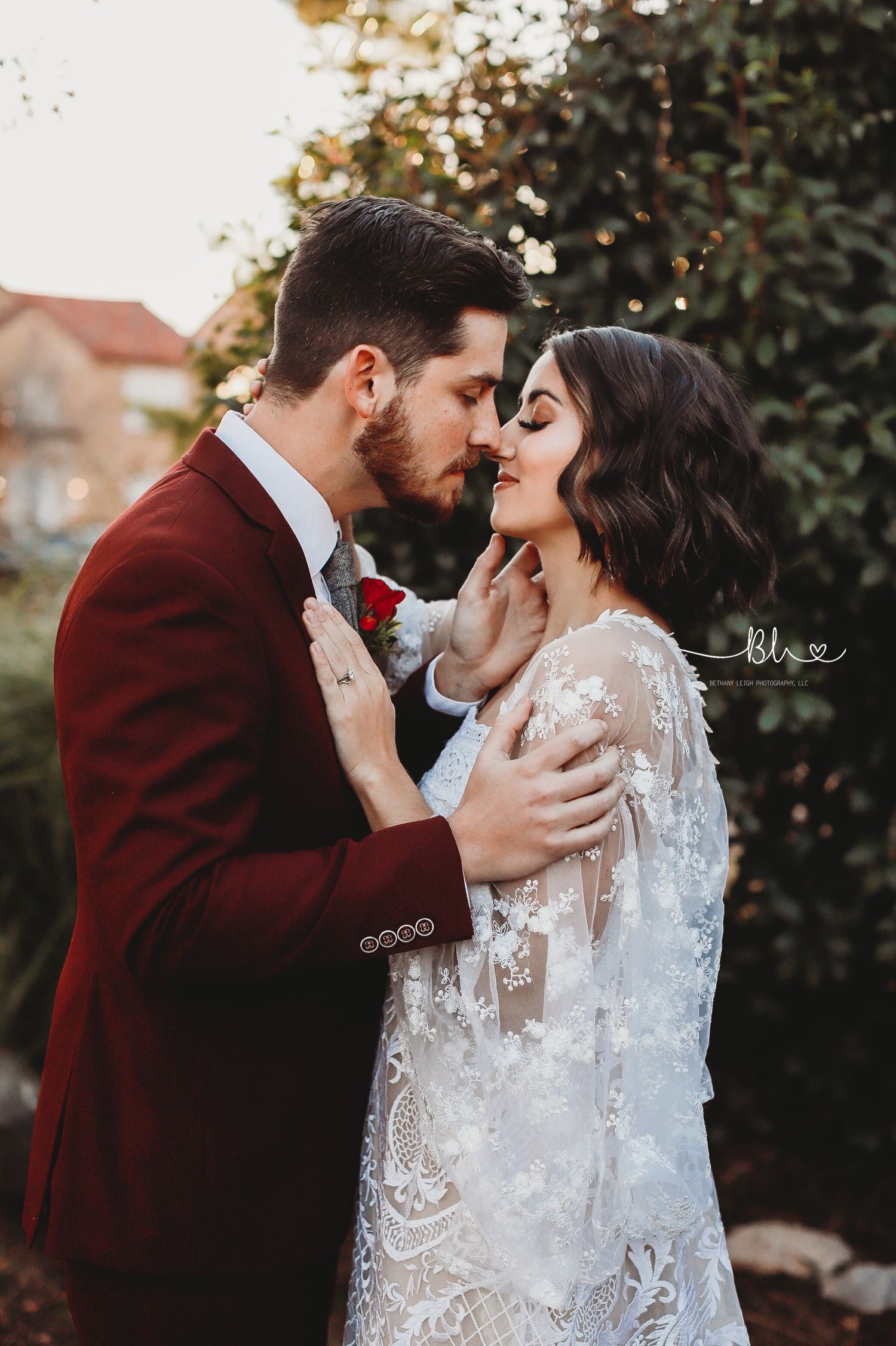 An intimate outdoor wedding portrait with burgundy and lace details.