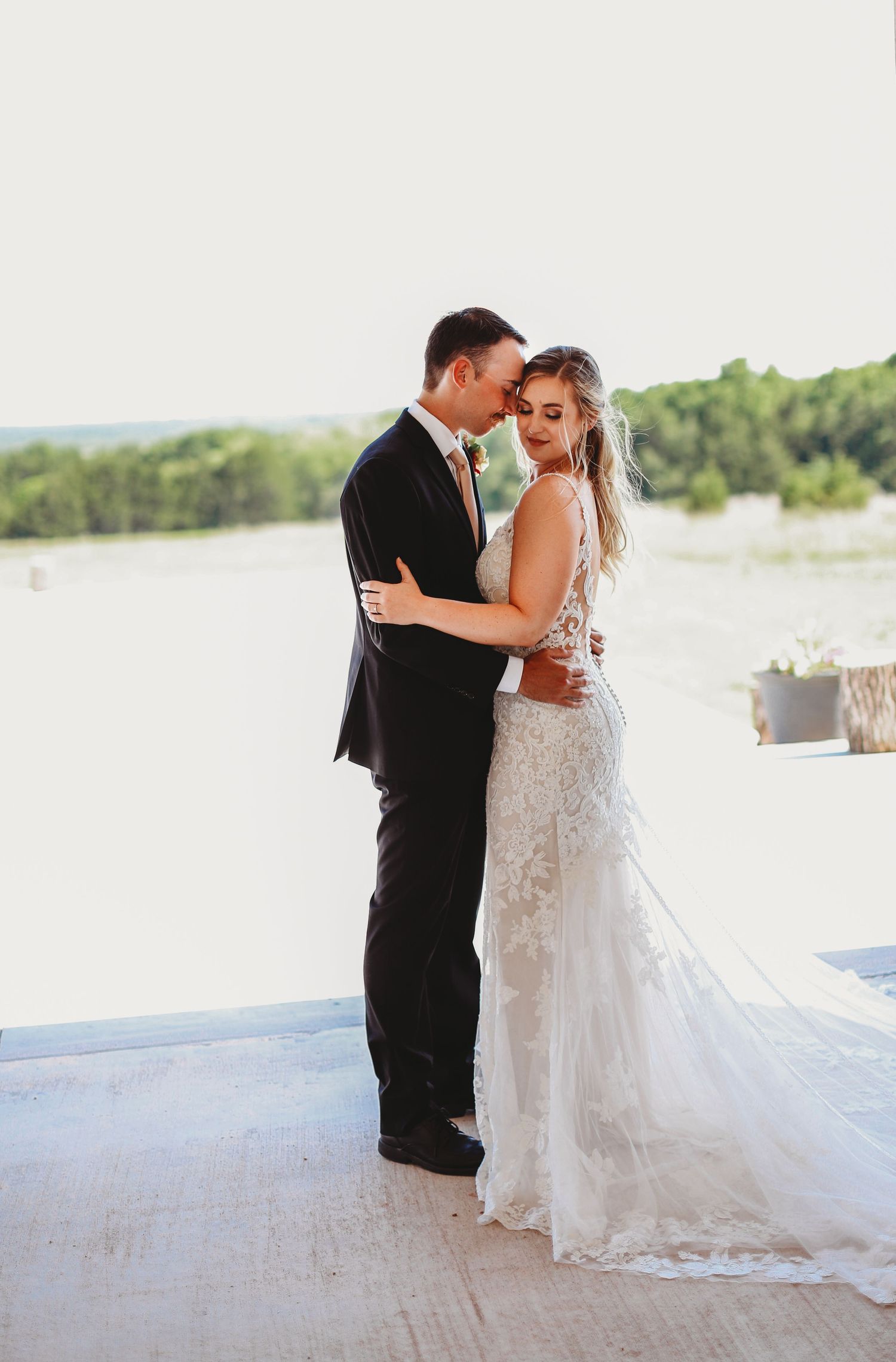 Elegant couple shares intimate moment on covered porch overlooking water.