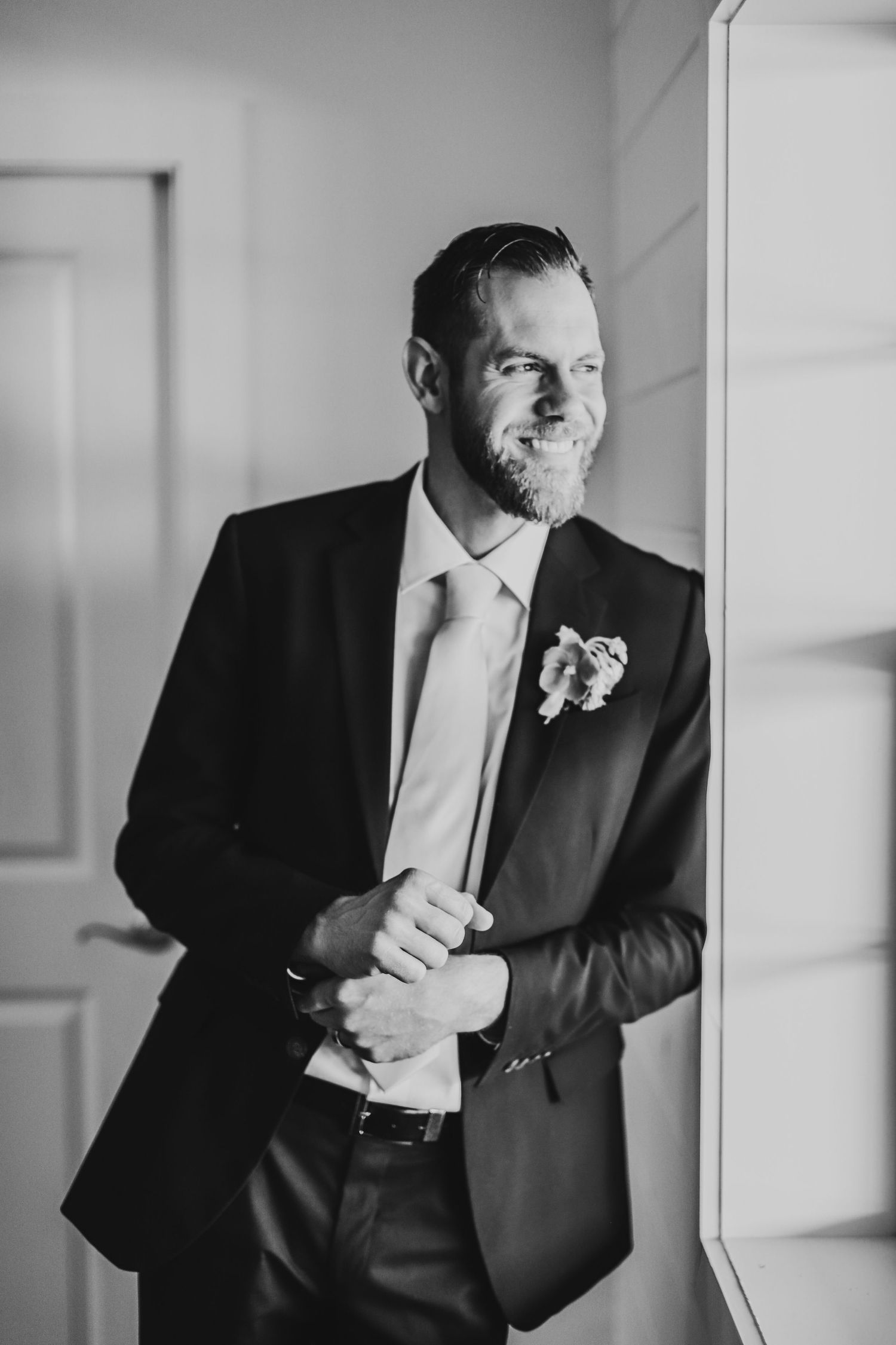 Black and white portrait of groom in classic suit with boutonniere.