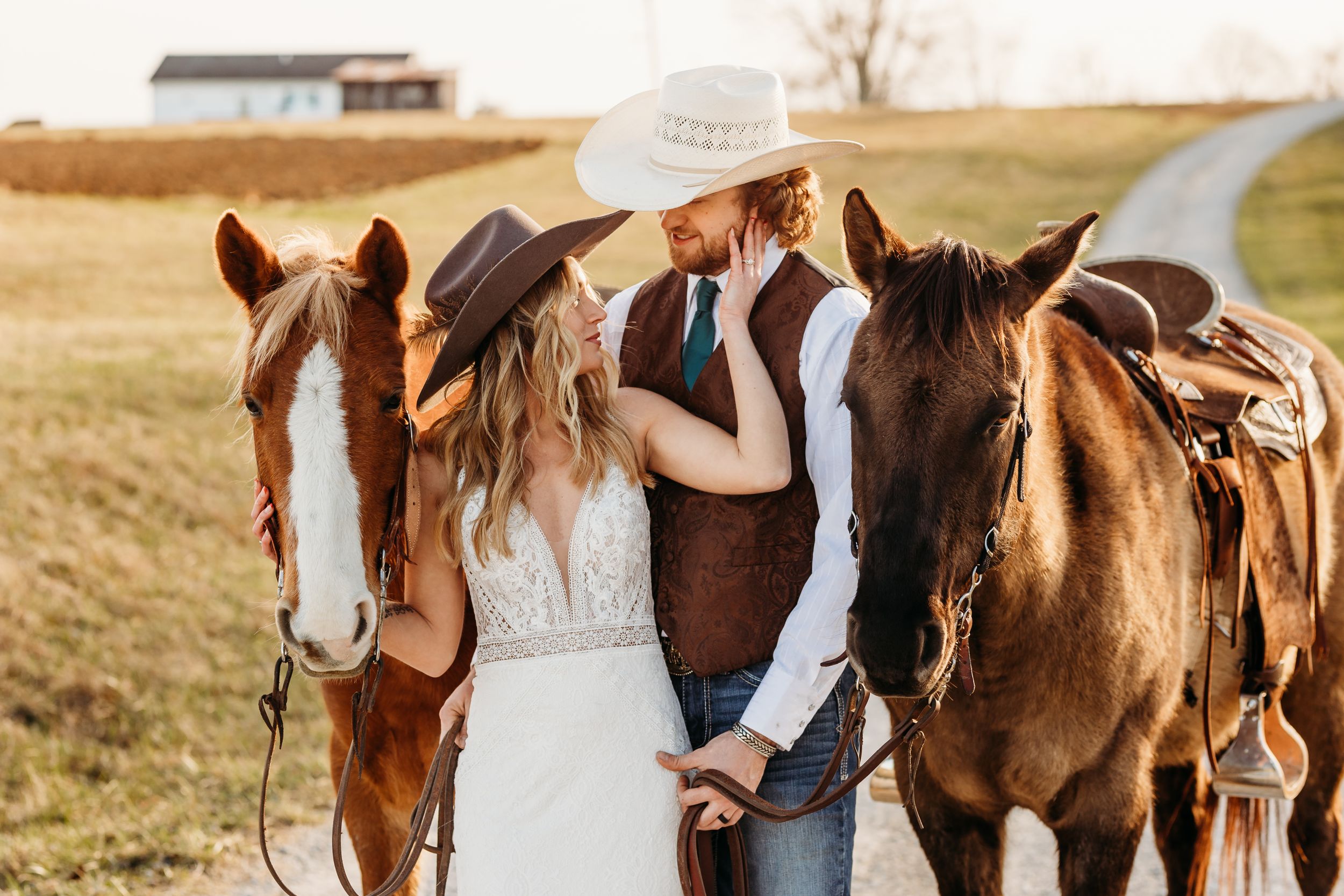 A romantic wedding couple shares an intimate moment between their horses at sunset.