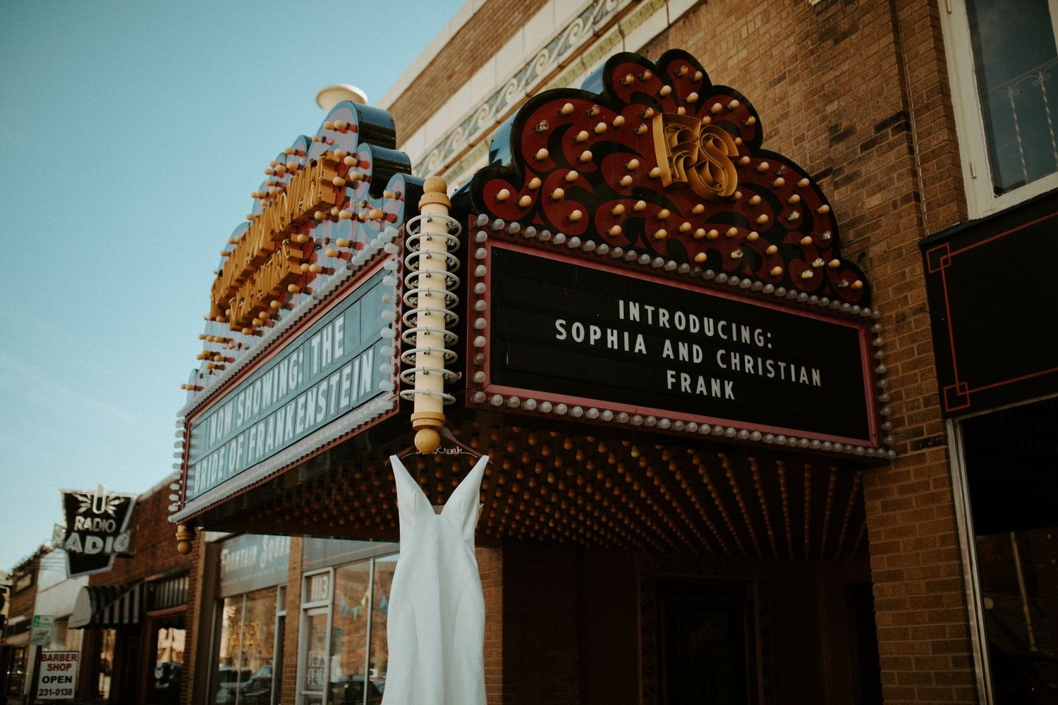 Wedding dress displayed under a vintage theater marquee introducing newlyweds Sophia and Christian Frank.