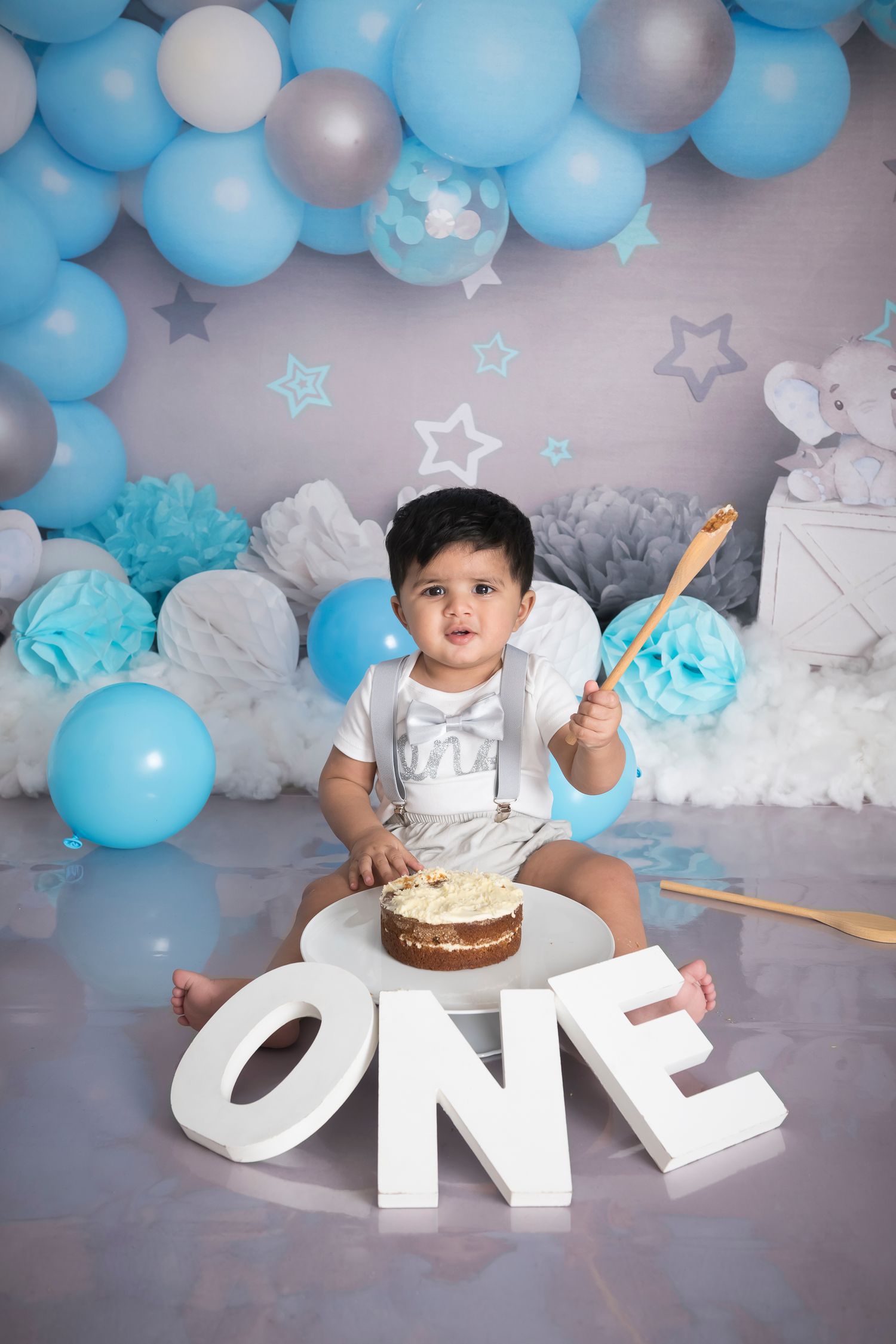 First birthday celebration setup with blue and silver balloons, stars, and a cake smash arrangement.