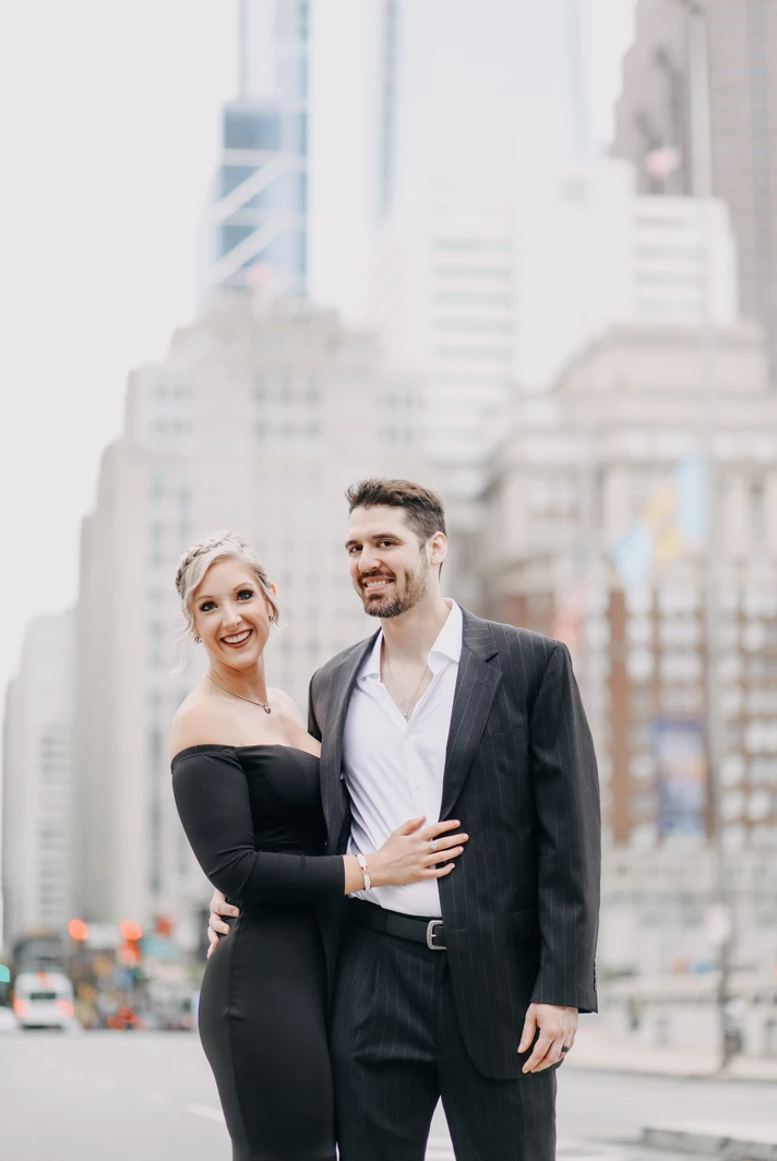 Elegant couple in formal attire pose against city skyline.