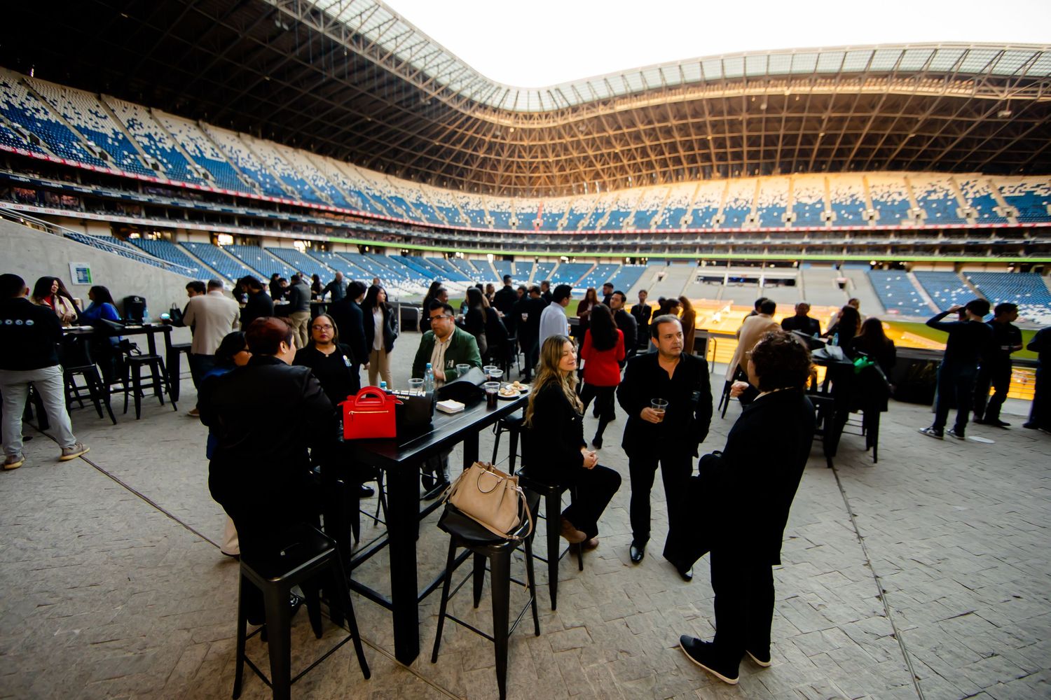 Guests mingling at an outdoor evening event inside a large stadium venue.