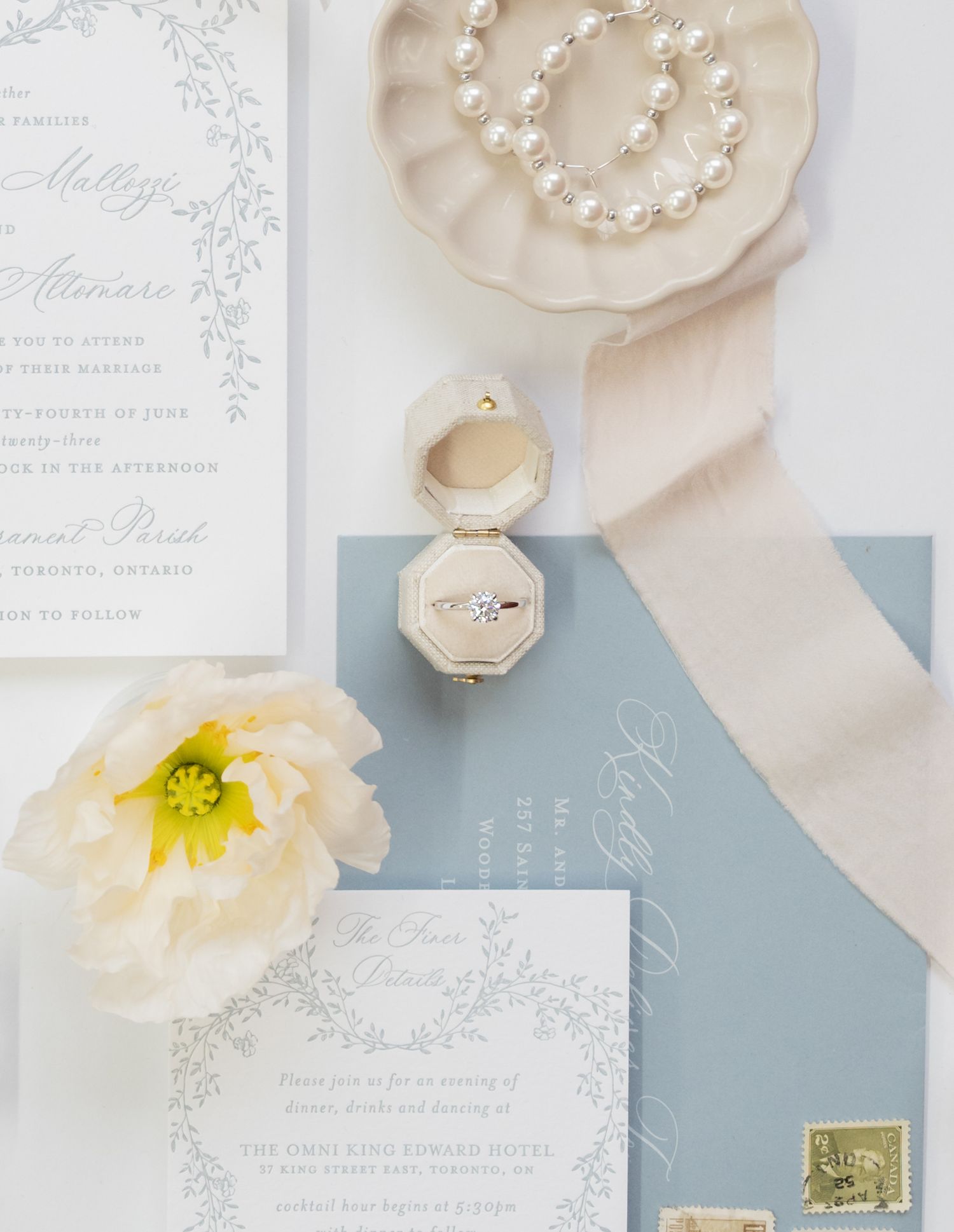 Wedding stationery suite with pearl necklace, light blue accents, and white peony flower.