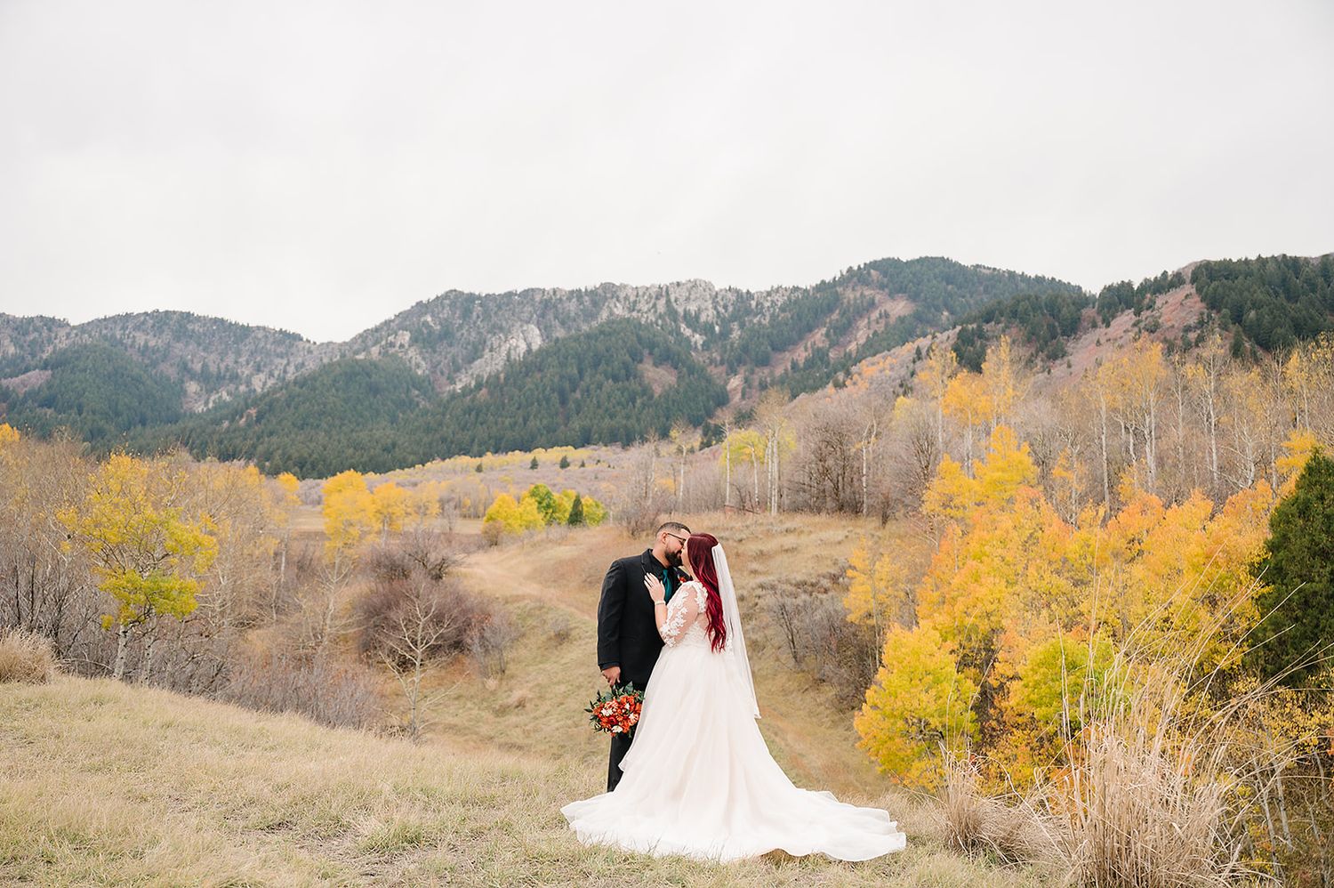 A wedding photograph featuring golden aspen trees and mountain views in autumn.