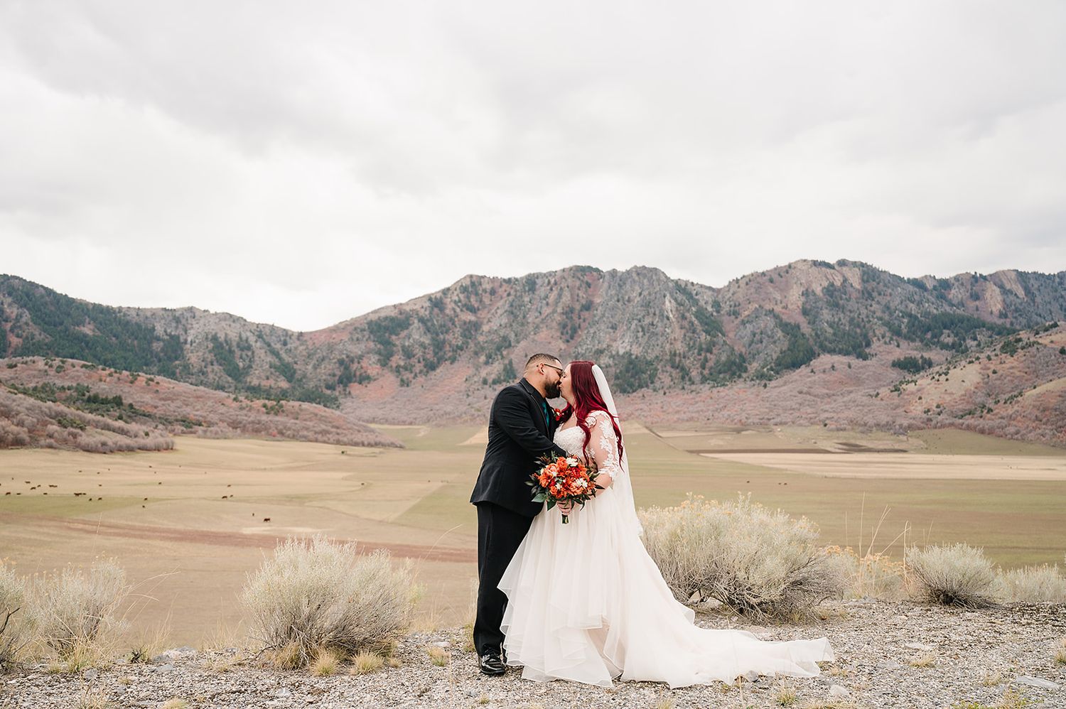 A romantic mountain wedding portrait with dramatic rocky landscape in the background.