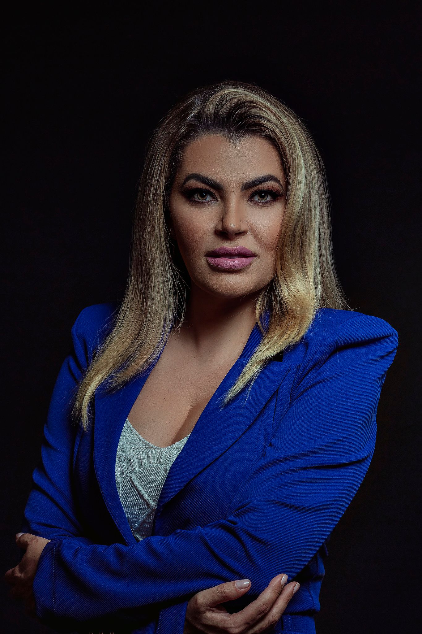 Professional headshot featuring a bright blue blazer against dark background.