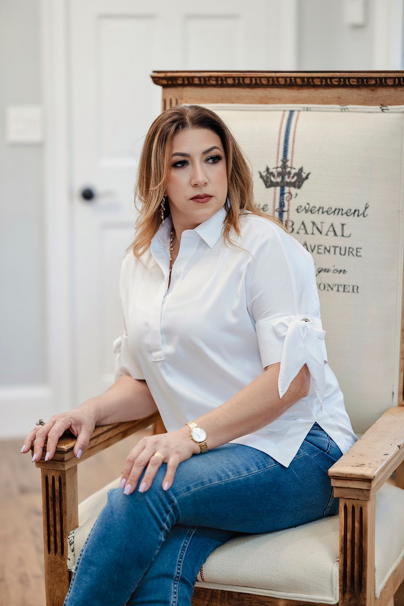 Casual business look with white button-down shirt and jeans in bright interior.