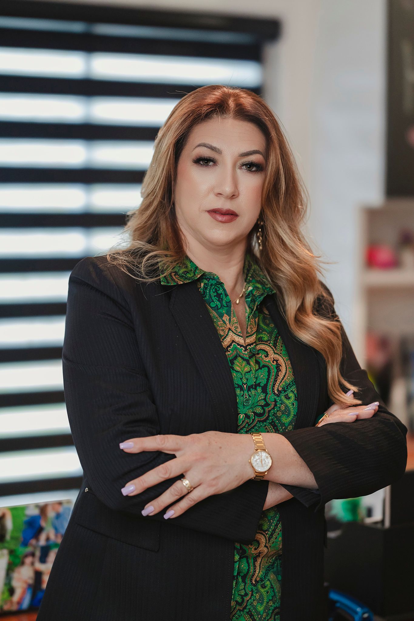 Business attire with emerald green blouse and black blazer in office setting.