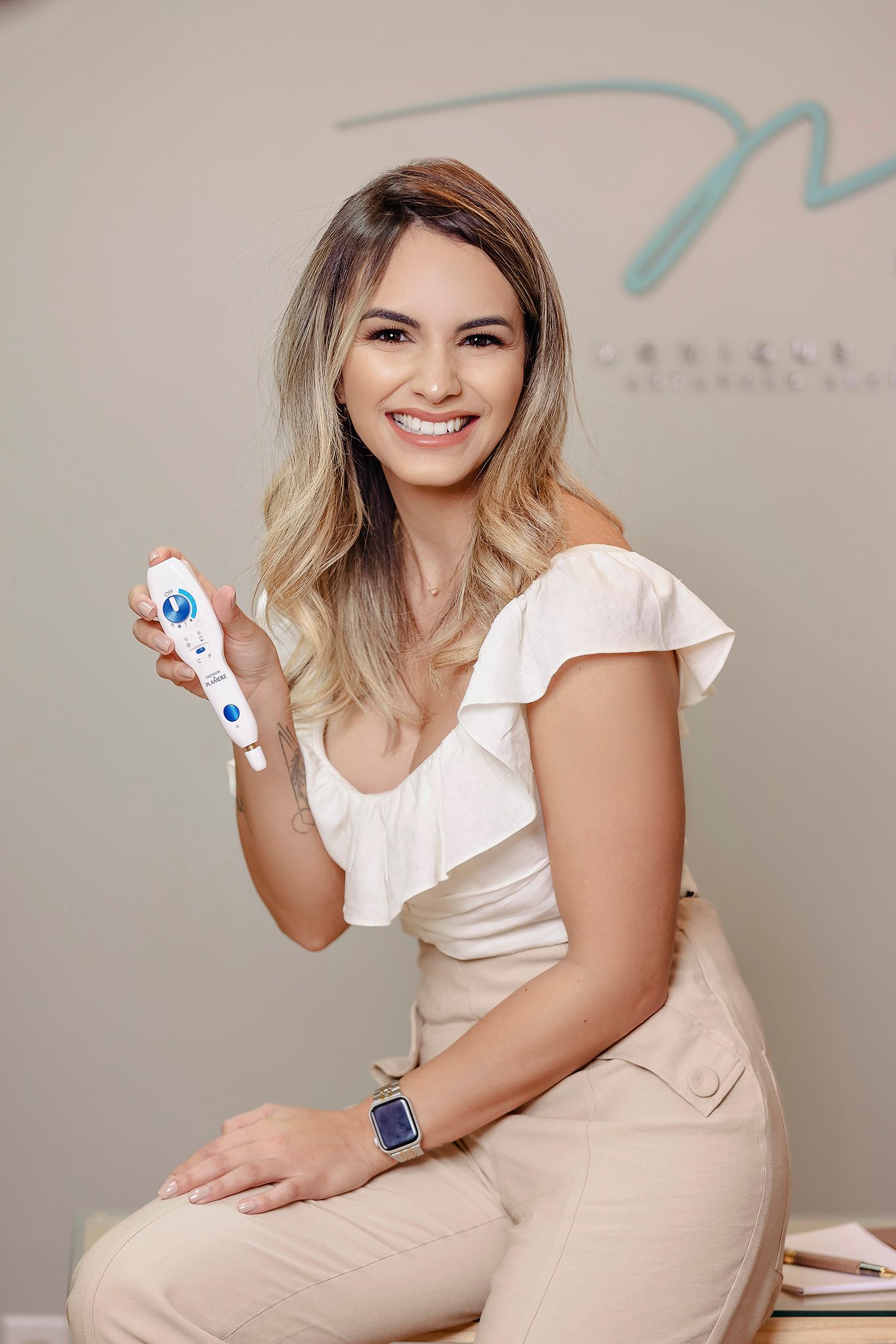 Beauty professional in cream-colored outfit holding skincare product.