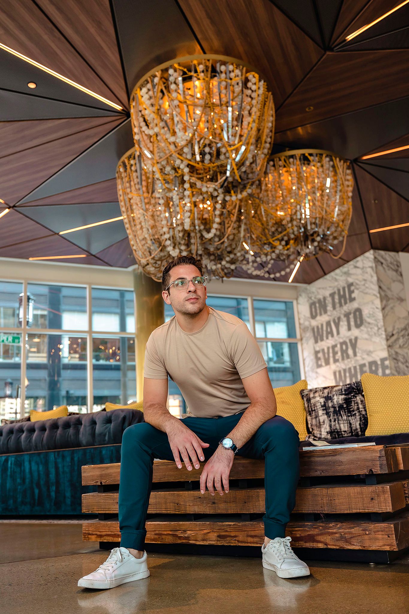 Person seated beneath elegant crystal chandelier in modern restaurant interior.