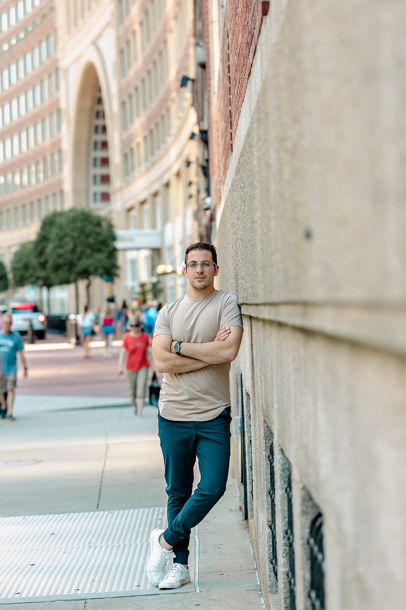 Urban lifestyle portrait of person in casual wear leaning against architectural wall downtown.