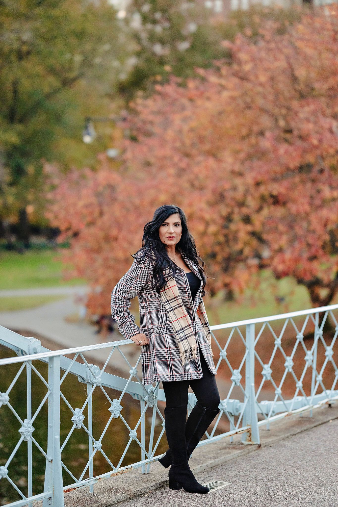 Autumn fashion portrait on bridge with fall foliage in background.