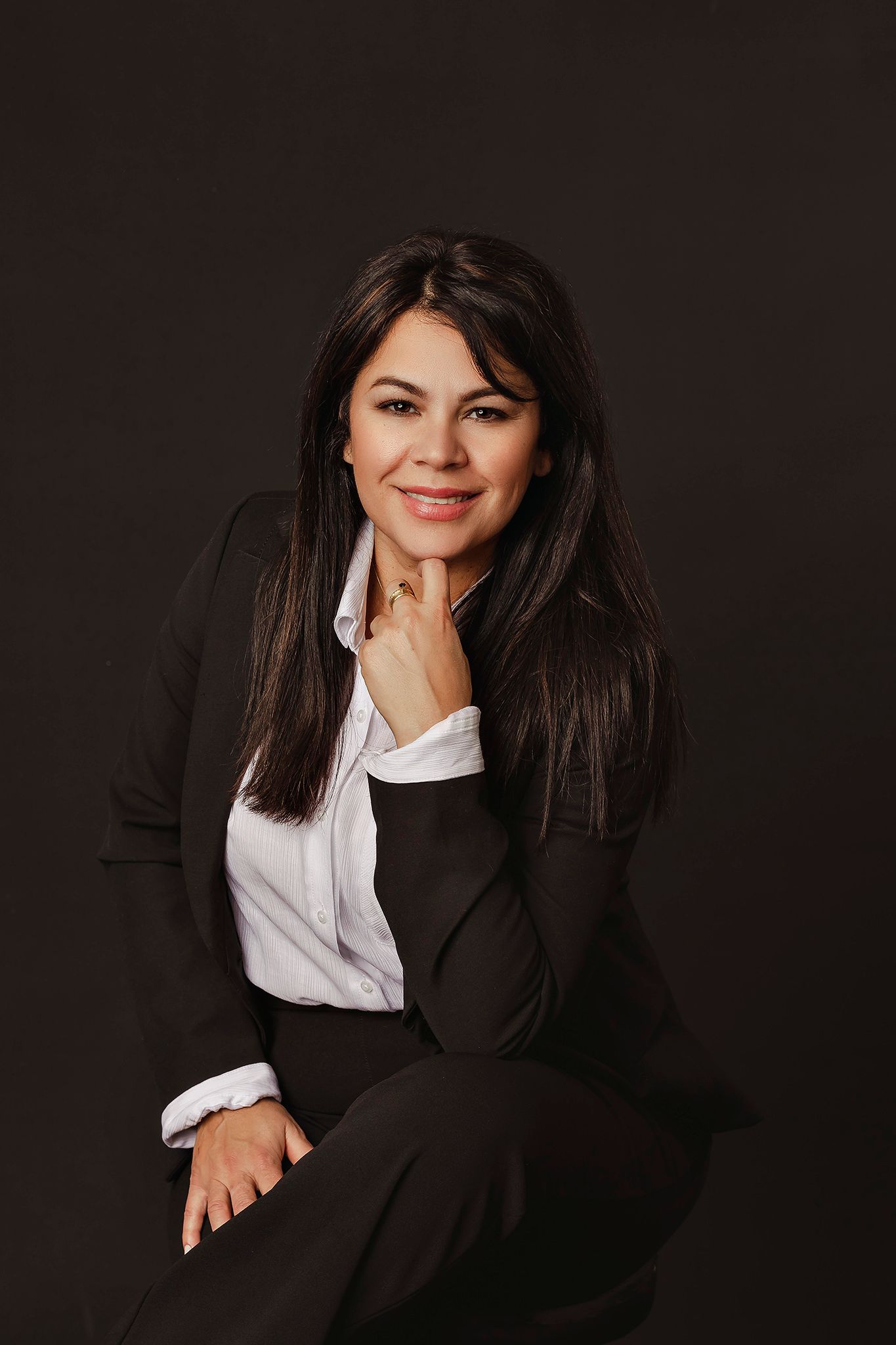 Dramatic studio portraits in black business suit with white collar against dark background.