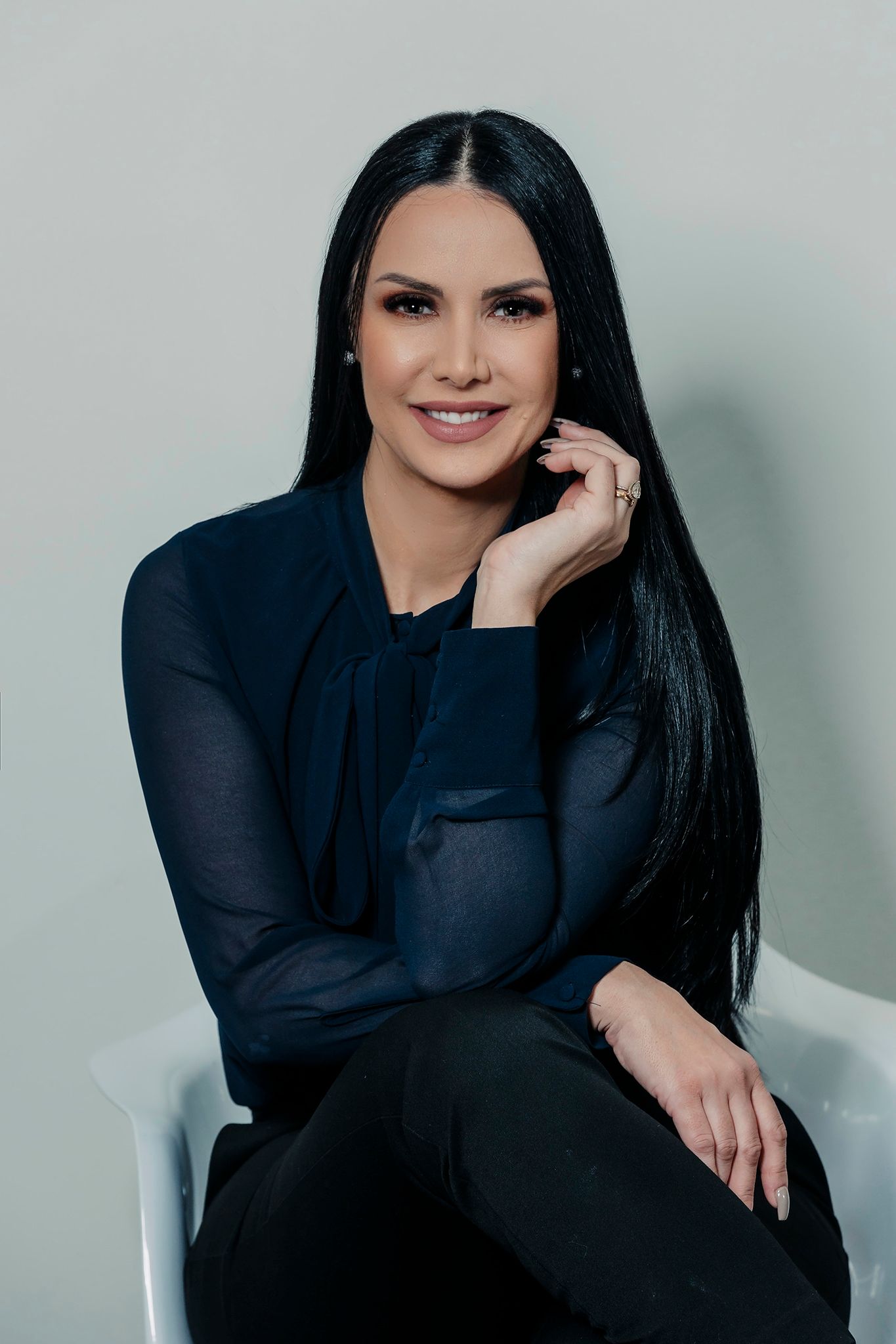 Studio portrait in navy blouse seated against neutral background.