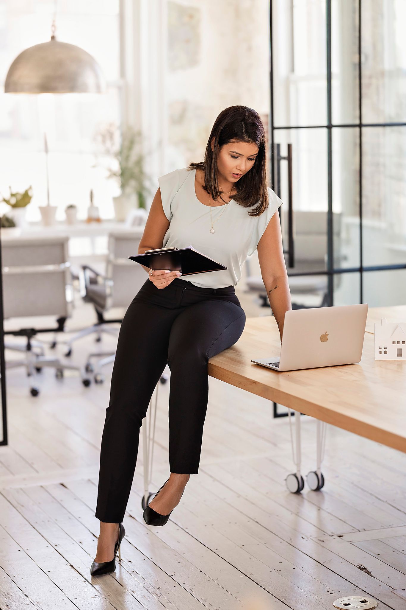 Business professional reviewing documents while working at standing desk in modern office.