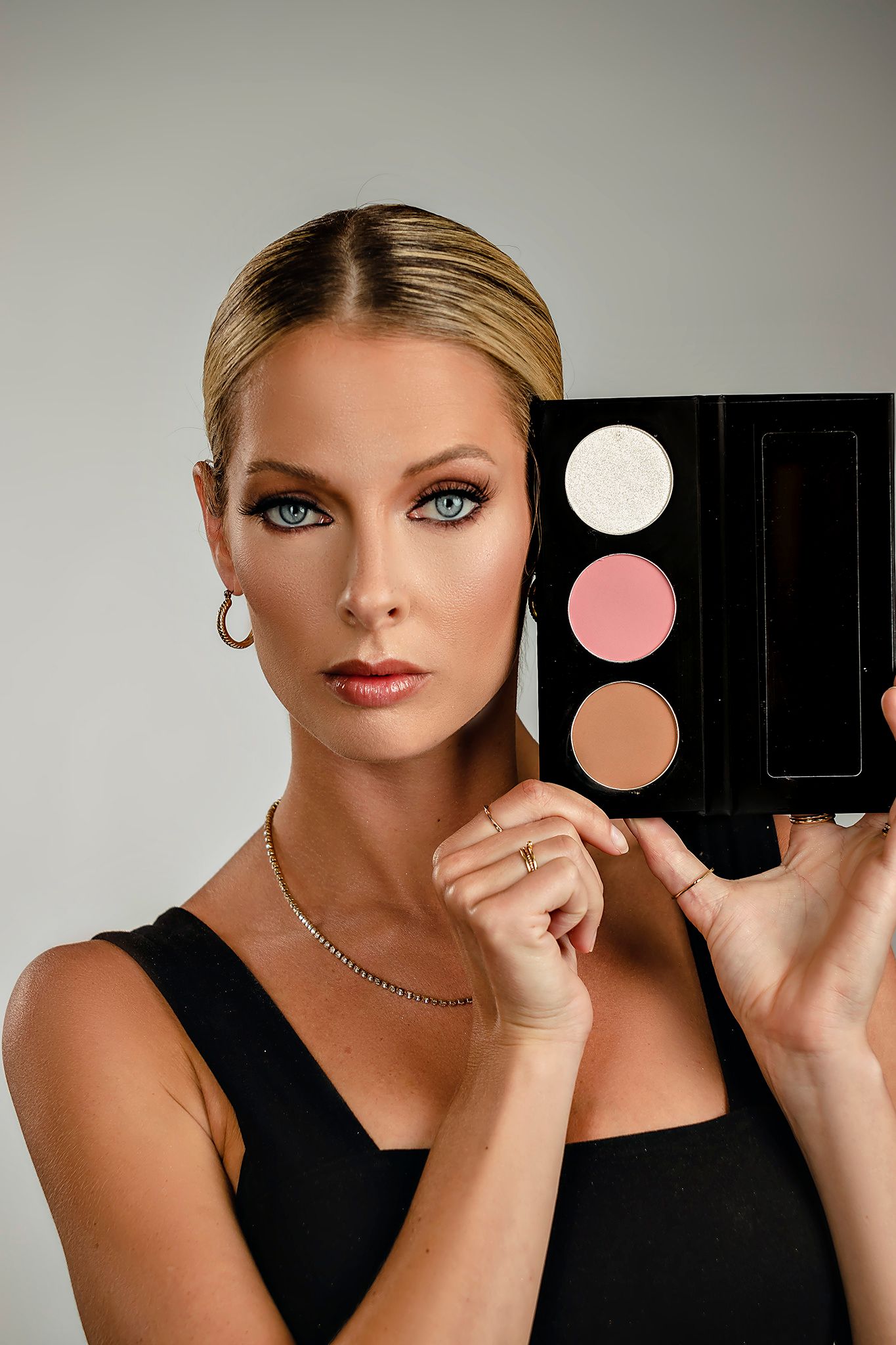 Professional beauty product photoshoot featuring makeup palettes against light gray background.