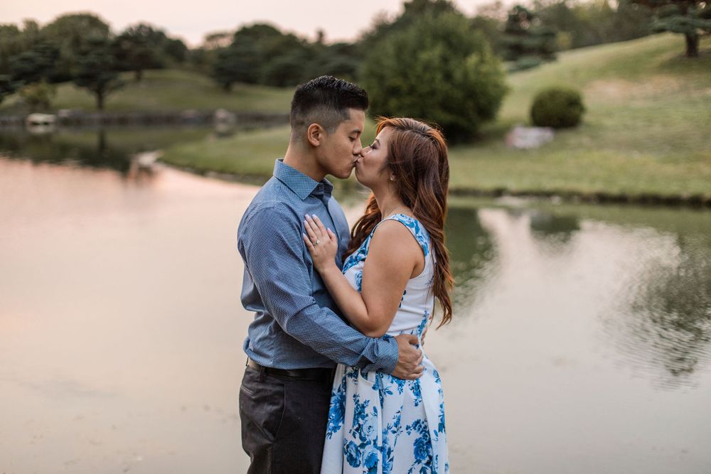A romantic couple embraces by a lake during sunset.