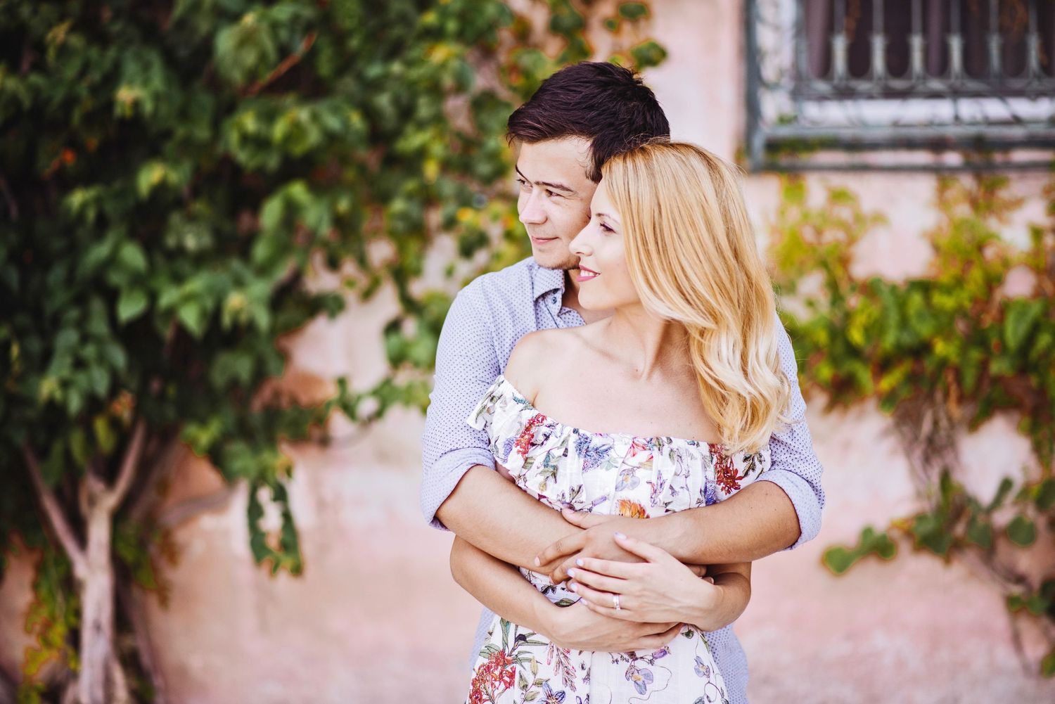 Romantic embrace in a lush garden setting with soft natural lighting and flowering plants.