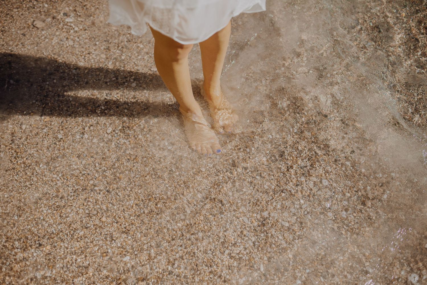 Footprints in the sand along a pristine beach with gentle waves lapping at the shore.