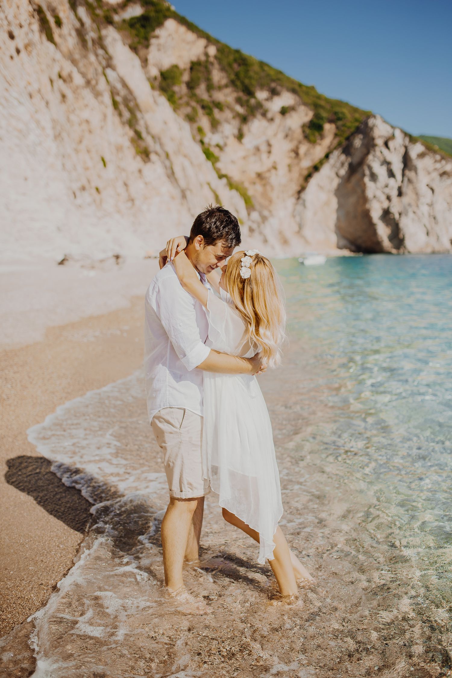 Romantic moment captured on a secluded beach with white limestone cliffs and turquoise waters.