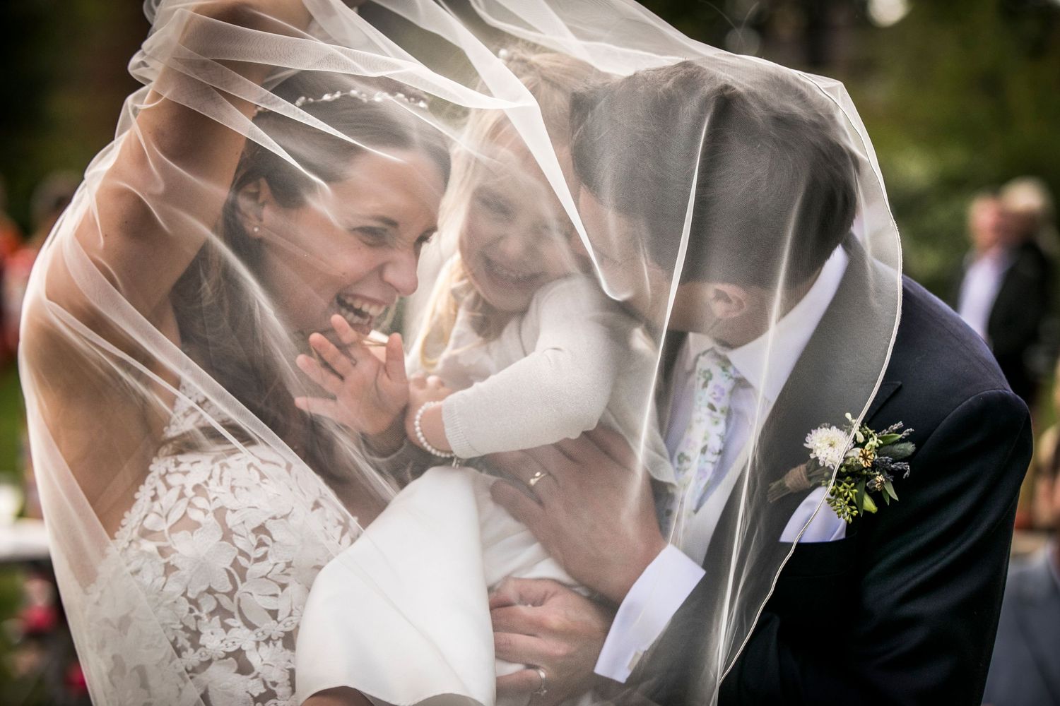 Romantic wedding portrait with flowing veil creating ethereal effect.