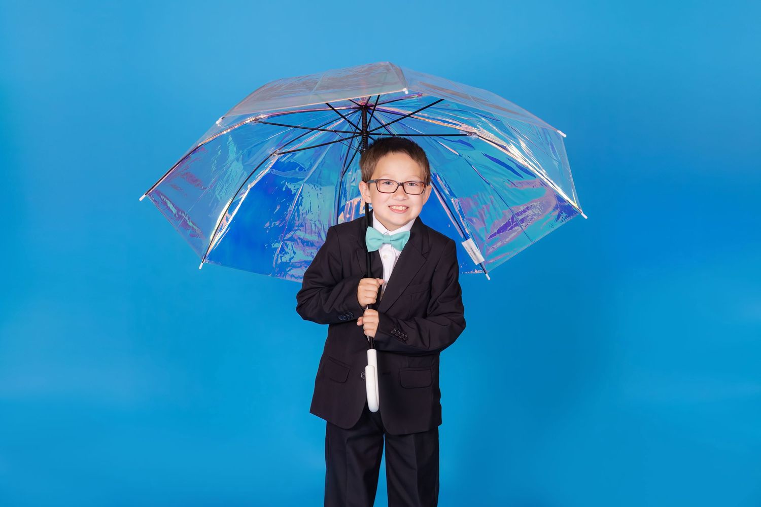 child in suit and bowtie holding iridescent umbrella on savage blue jay backdrop in studio clayton new jersey Gloucester