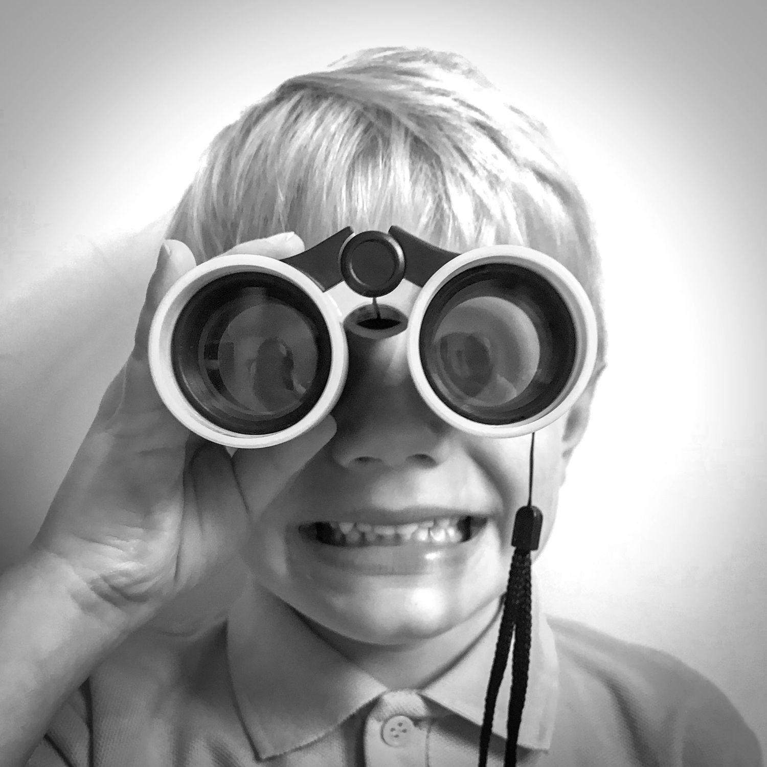 Funny black and white image of Theo looking at the camera through binoculars.