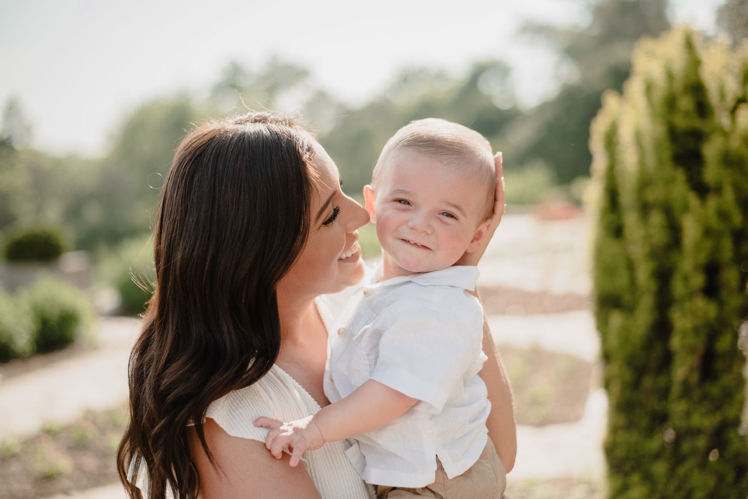A joyful outdoor portrait showing a heartwarming connection between parent and child against a natural backdrop.