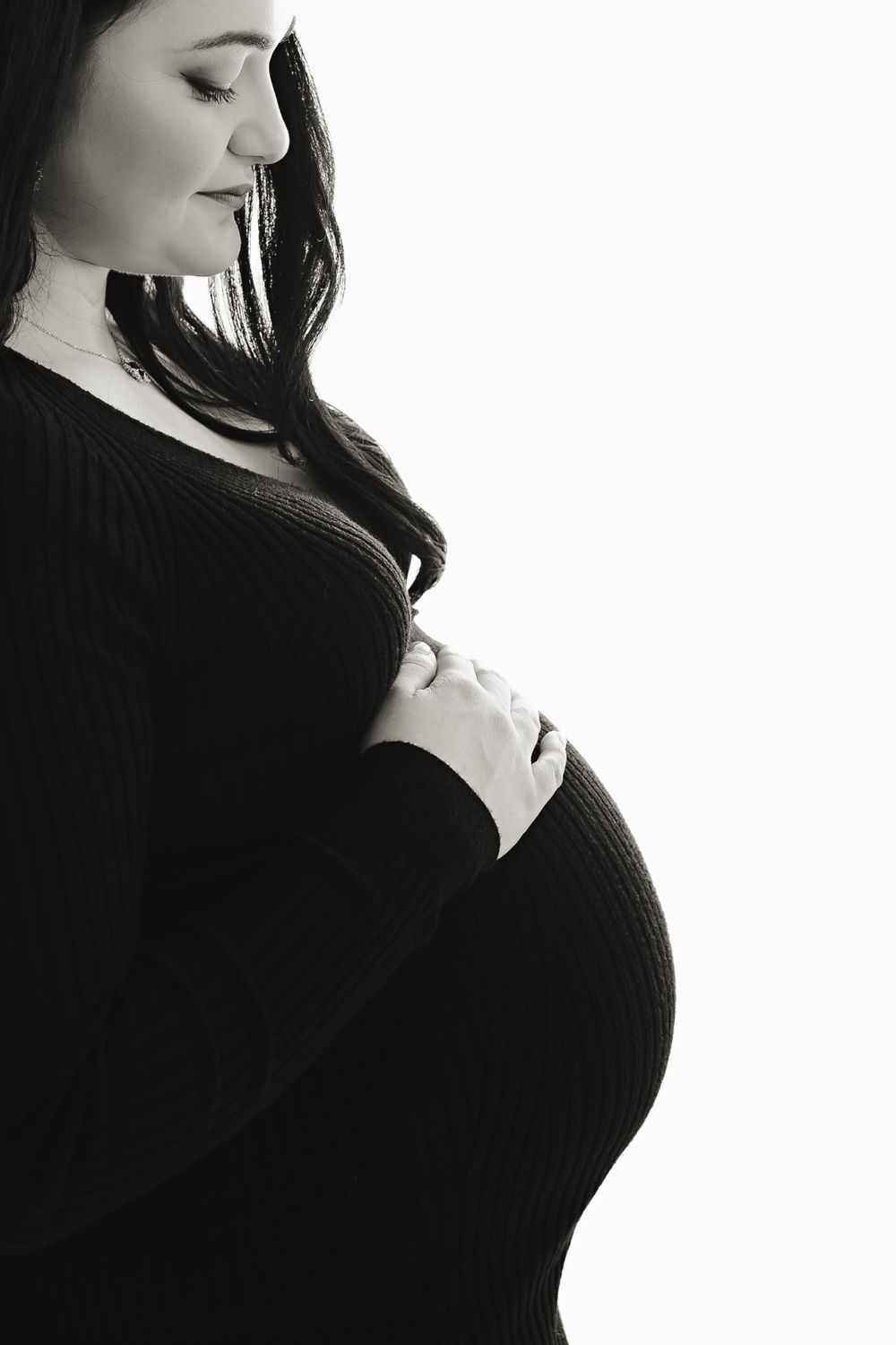 Artistic maternity silhouettes in black and white against white background.