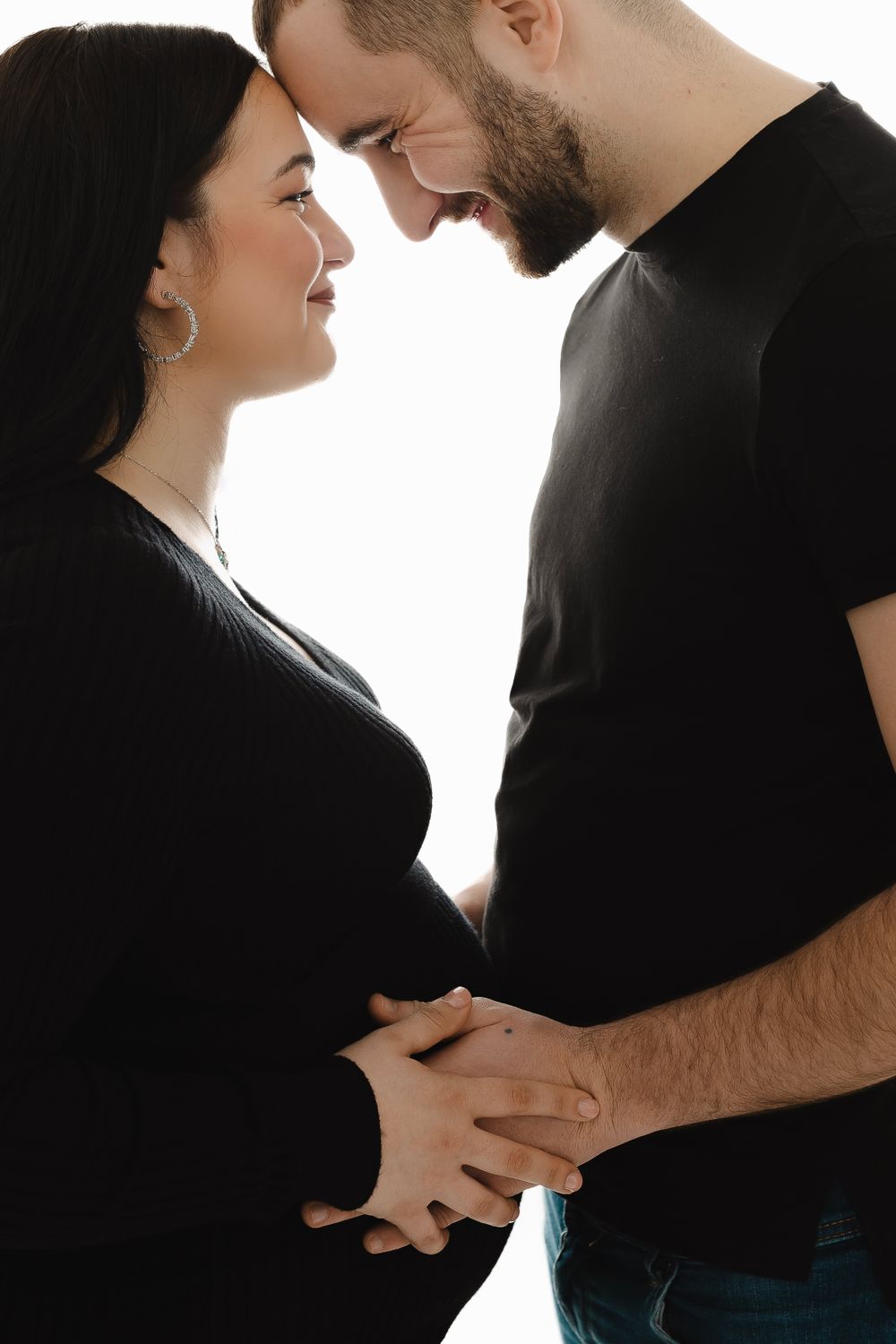 Artistic black and white pregnancy photos capturing loving embrace against white background.
