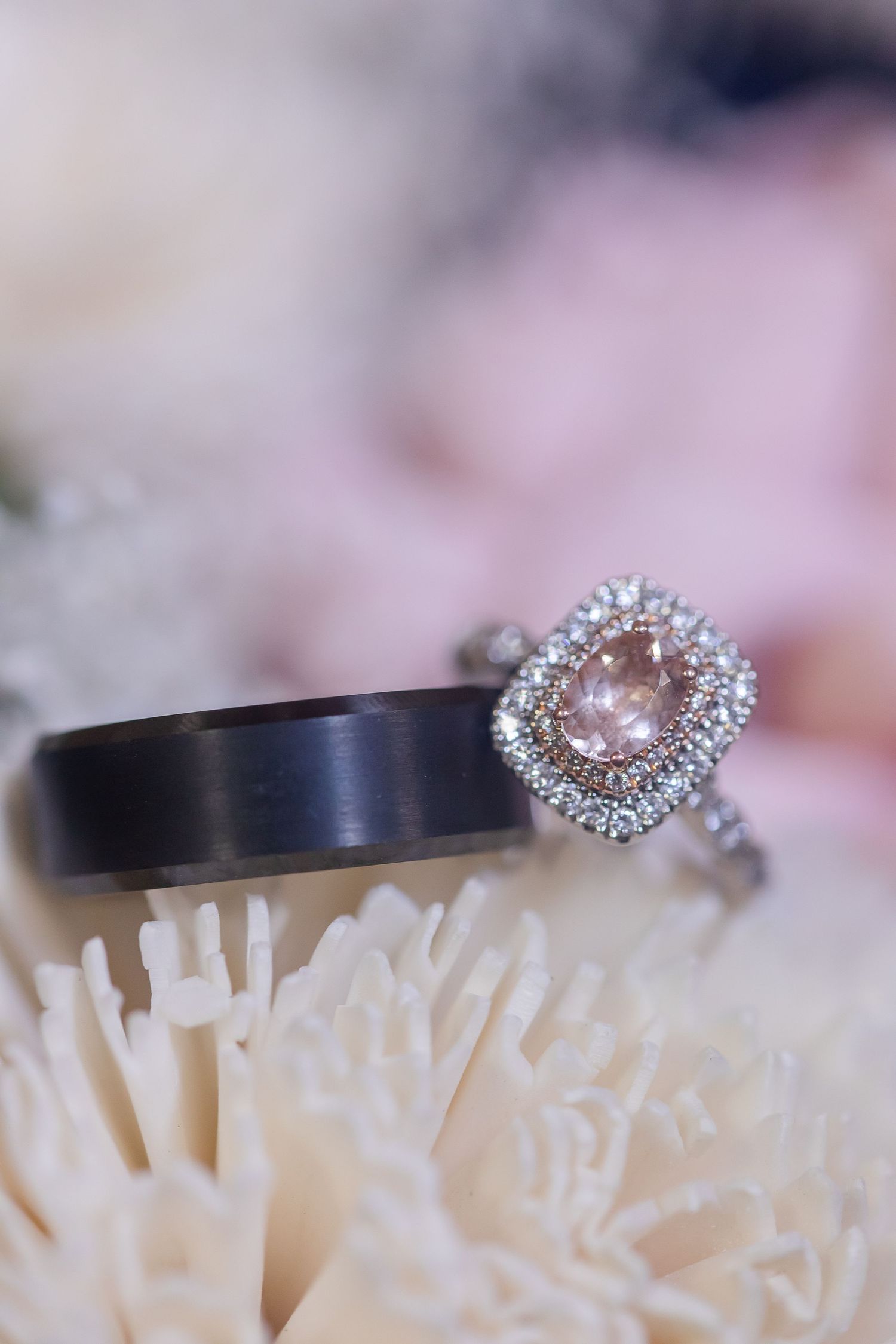 Detailed shot of engagement and wedding rings arranged on a textured white surface.