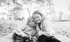 Two siblings sharing a sweet moment while playing with autumn leaves.