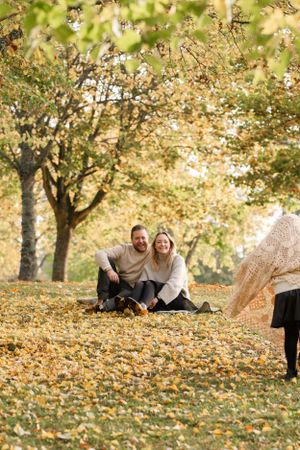 Candid outdoor family moment in a park filled with golden autumn leaves.
