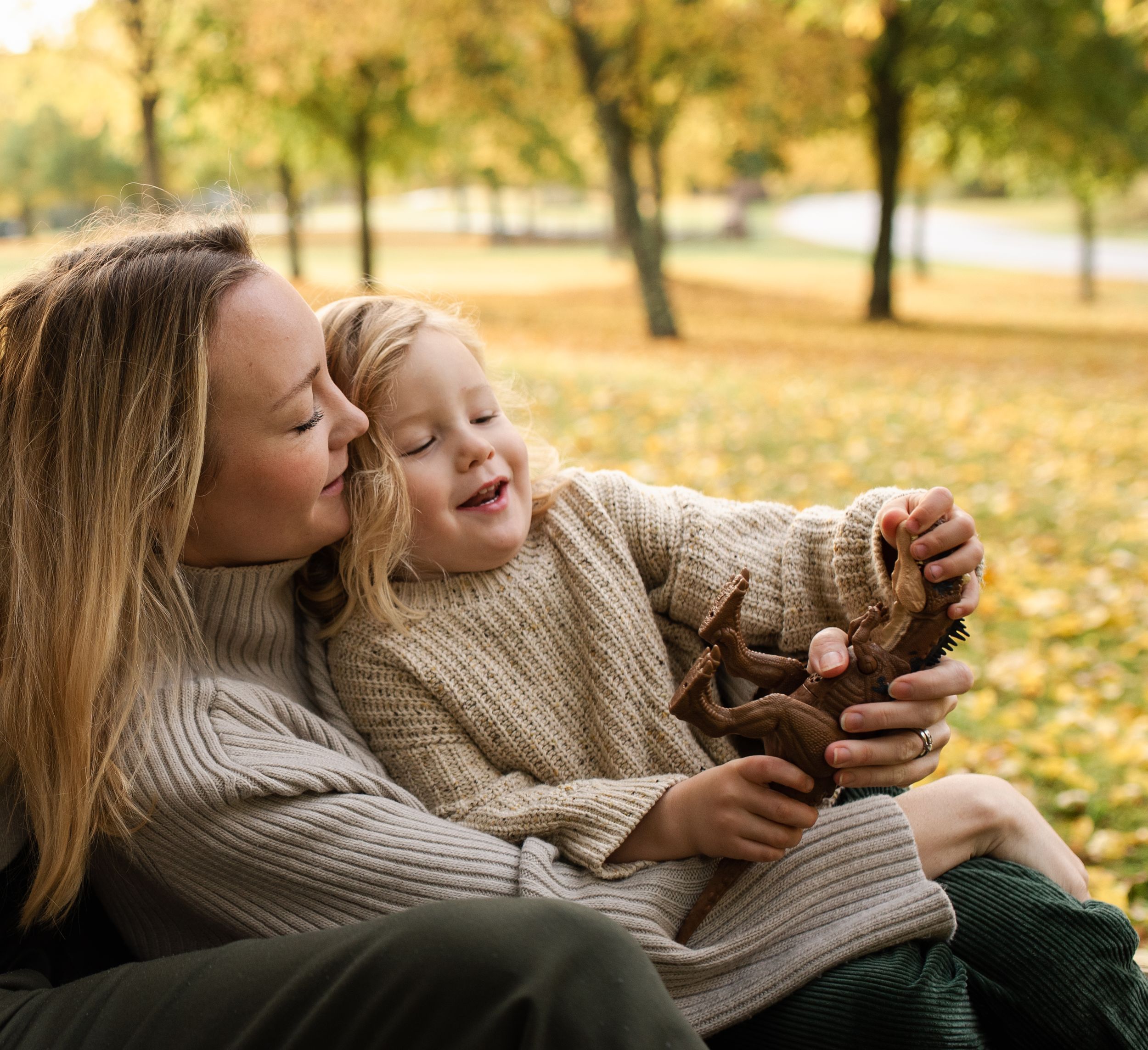 Tender moment shared while collecting autumn leaves in matching sweaters.