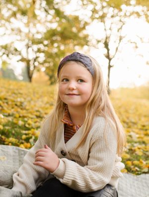 A warm autumn portrait with golden leaves and sunlight in the background.
