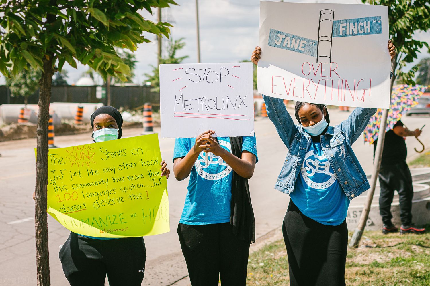 three black folks holding one poster each, advocating for Jane and Finch community
