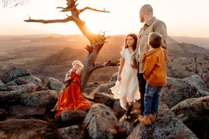A family enjoying sunset together on rocky mountain terrain.