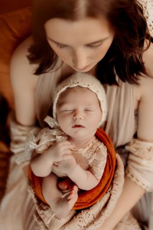 Tender moment between parent and infant in soft sepia tones.