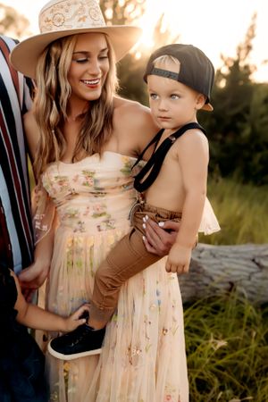 A sunset photoshoot features a flowing floral dress and natural outdoor setting with warm golden light.
