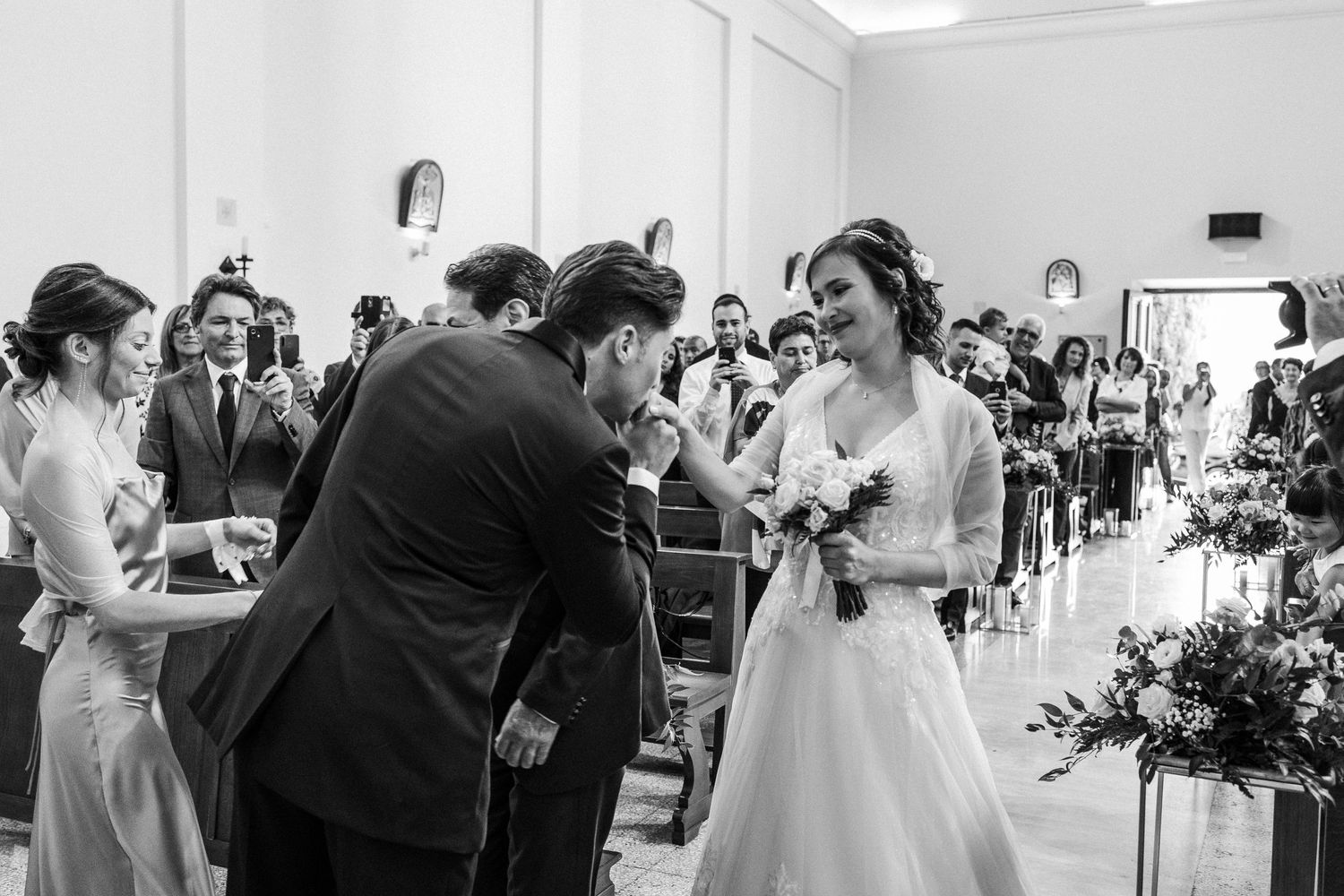 Black and white photo capturing joyful moment during indoor wedding ceremony.