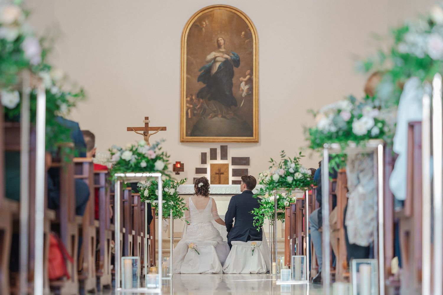 Interior view of a church decorated with greenery and floral arrangements during a wedding ceremony.