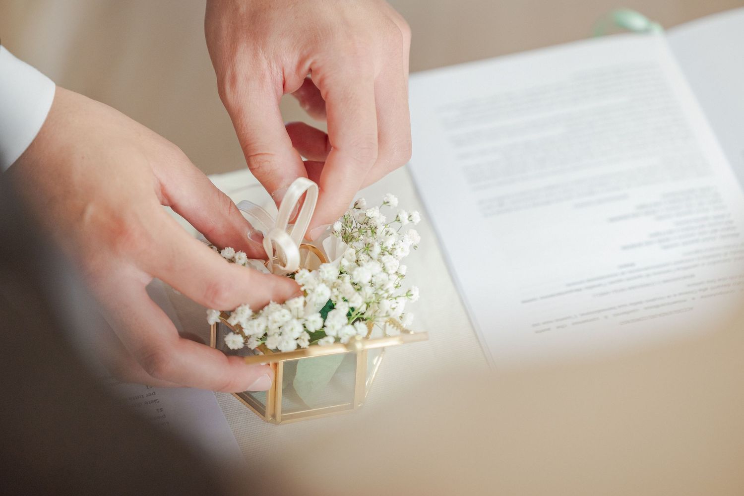 Close-up of hands delicately handling small white flowers and a decorative box.