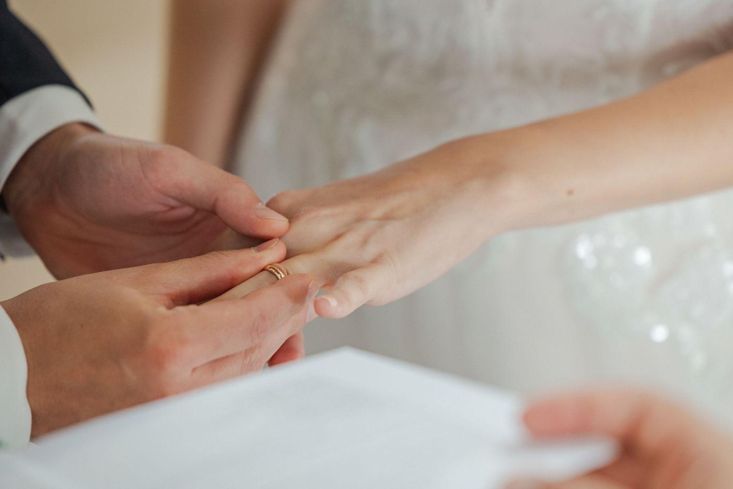 Gentle exchange of rings during a wedding ceremony with hands in focus.