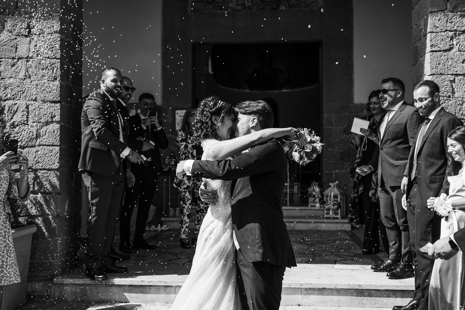 Celebratory moment outside church entrance with confetti in black and white.
