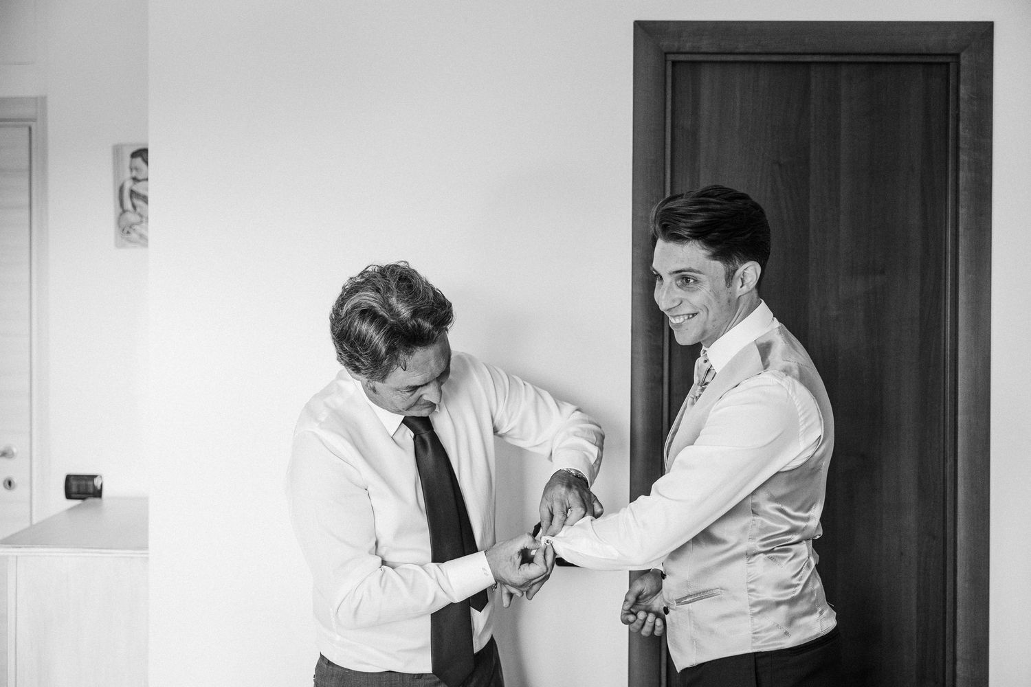 A black and white photo captures a moment of adjusting formal wear buttons.
